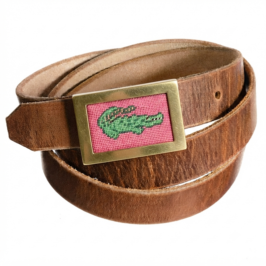Brown Horween leather FFF belt strap coiled, fitted with a Heather Rae Atelier brass buckle holding a pink needlepoint alligator canvas.